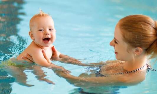 Lachendes Baby beim Babyschwimmen mit Mutter im AQUAFUN Fleesensee